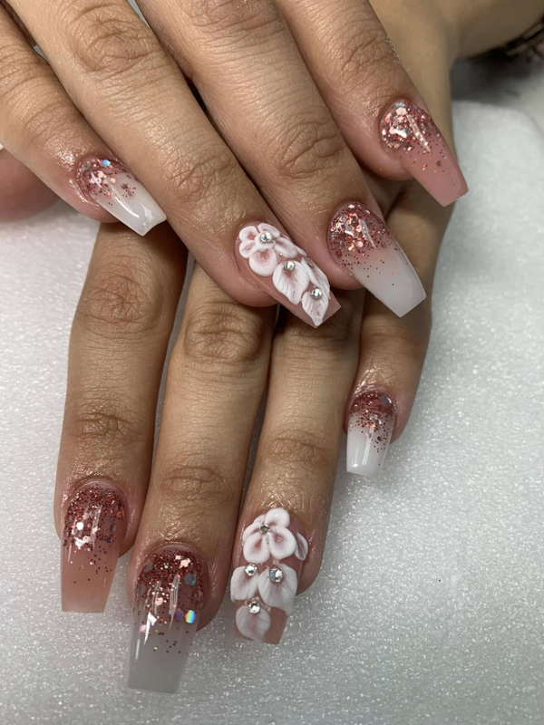 Rose-gold glitter ombré coffin nails with white 3D floral accents